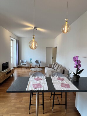 Een moderne woonkamer met een eethoek, een televisie en een bank.