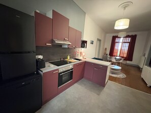 Eine kleine Küche mit Kühlschrank, Herd, Mikrowelle und Spüle.