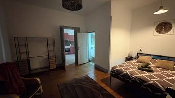 Een slaapkamer met een bed, een stoel, een kledingkast en een deur naar een balkon.