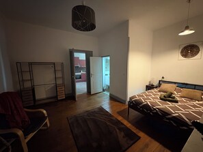 Ein Schlafzimmer mit einem Bett, einem Sessel, einem Kleiderschrank und einer Tür, die auf einen Balkon führt.