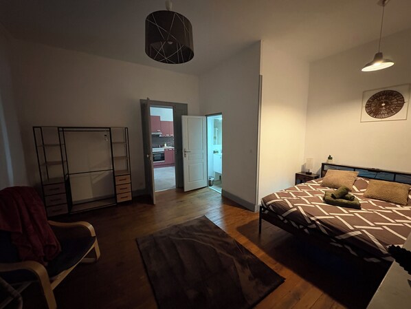 Une chambre à coucher comprenant un lit, une chaise, une armoire et une porte donnant sur un balcon.