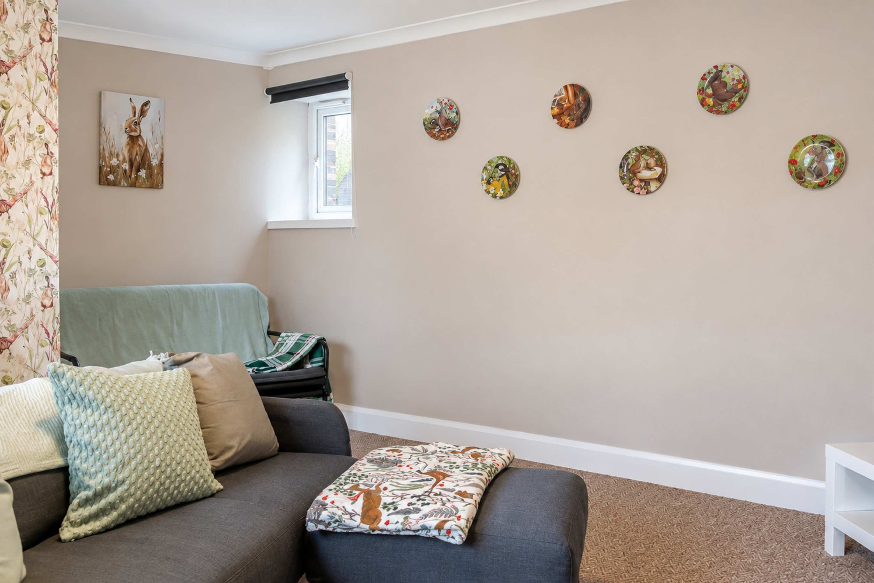 Un salon avec un canapé, une fenêtre et des éléments décoratifs sur les murs.