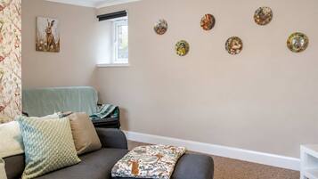 Un salon avec un canapé, une fenêtre et des éléments décoratifs sur les murs.