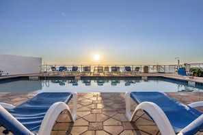 A pool area with lounge chairs and a view of the sunset. - Daytona Beach Escape with Partial Ocean Views, Private Balcony & Heated Pools (Daytona Beach)