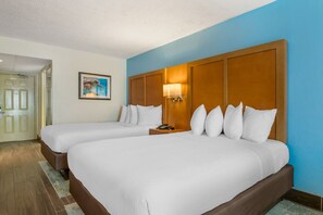 Ein Hotelzimmer mit zwei Betten, einem Holzkopfteil, einem Nachttisch und einem gerahmten Bild an der Wand.