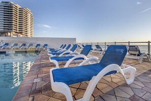 Ein Poolbereich mit Liegestühlen und Blick auf den Ozean.