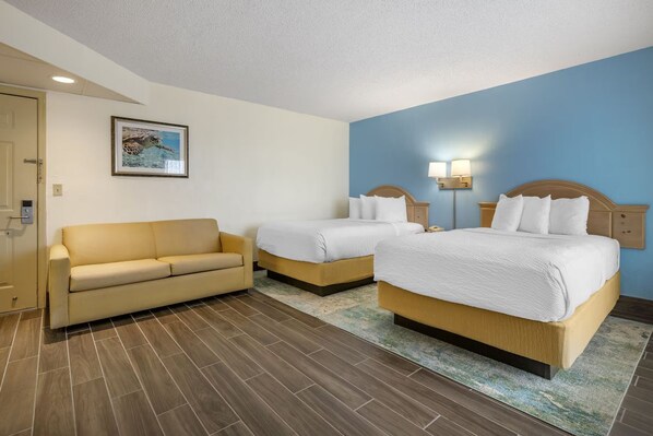 Ein Hotelzimmer mit zwei Betten, einem Schlafsofa und einem Bild an der Wand.