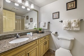 A bathroom with a sink, mirror, toilet, and towel rack. - Oceanfront Penthouse with Full Kitchen, Spacious Living Area & Private Balcony (Daytona Beach)