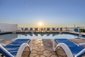 A pool area with lounge chairs and a view of the sunset. - Oceanfront Penthouse with Full Kitchen, Spacious Living Area & Private Balcony (Daytona Beach)