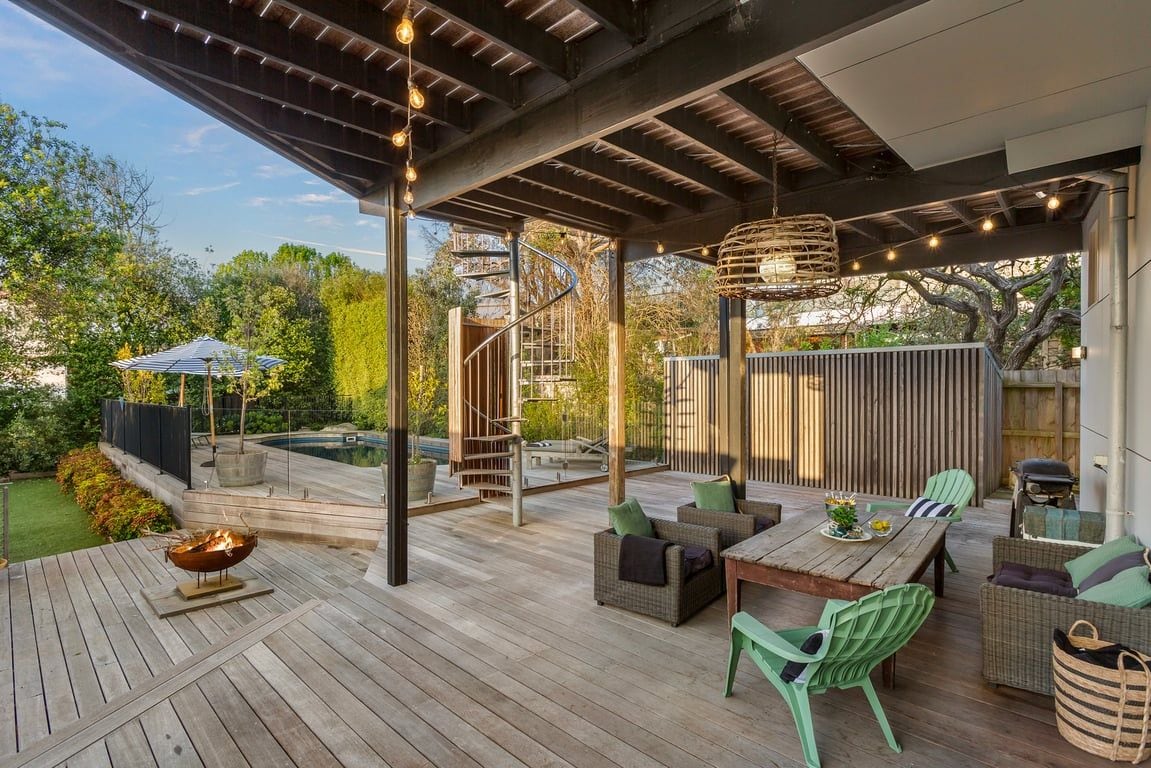 Une terrasse extérieure dotée d’un foyer, d’un espace salon et d’un escalier menant à un niveau supérieur.