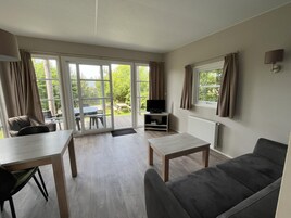 Un salon moderne comprenant un canapé, une table basse, un téléviseur et un coin repas avec une table et des chaises.