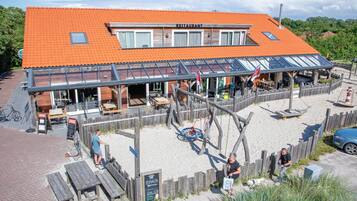 A restaurant with a red tiled roof, outdoor seating, and a wooden fence.