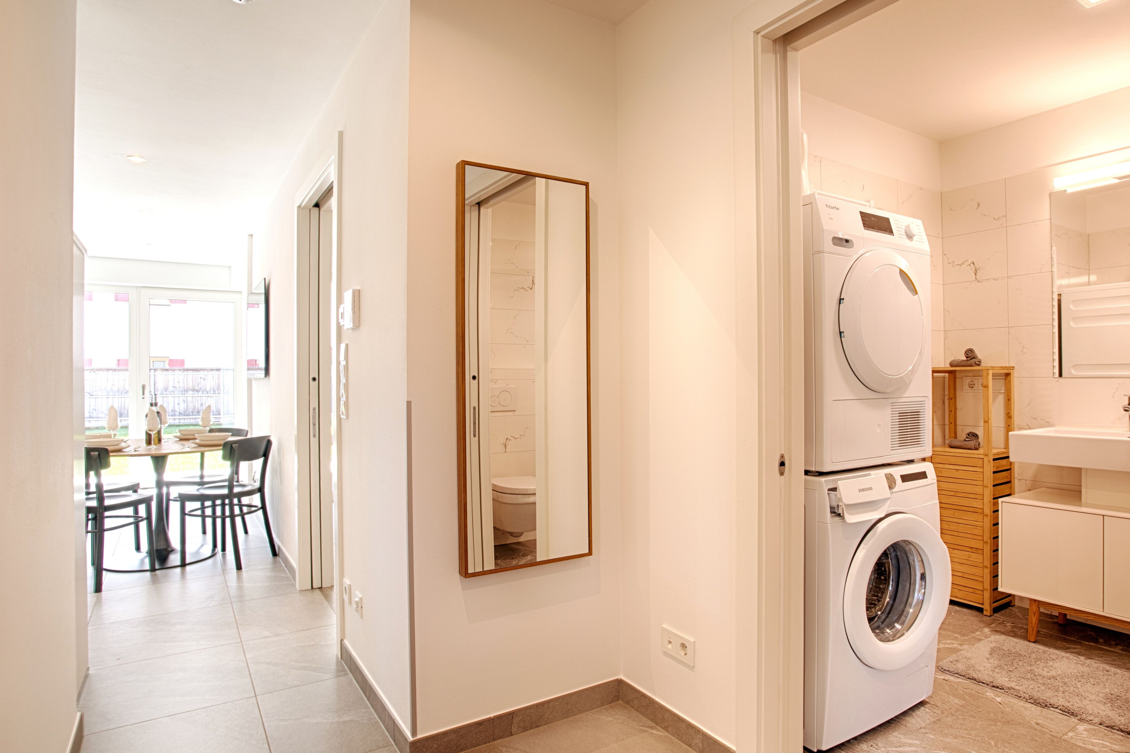 Ein modernes Badezimmer mit Waschmaschine, Spiegel und Holzschrank.