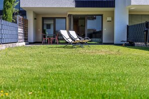 Ein modernes Gebäude mit Flachdach, überdachter Terrasse und gepflegtem Rasen.