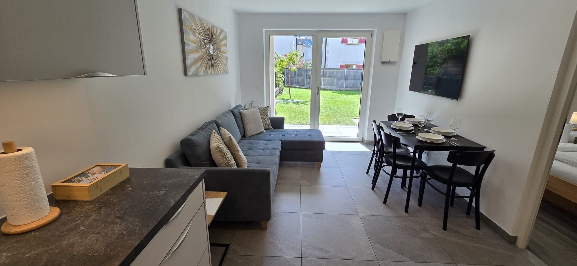 Ein gemütlicher, kompakter Wohnraum mit Küchenzeile, Essbereich und Sofa.
