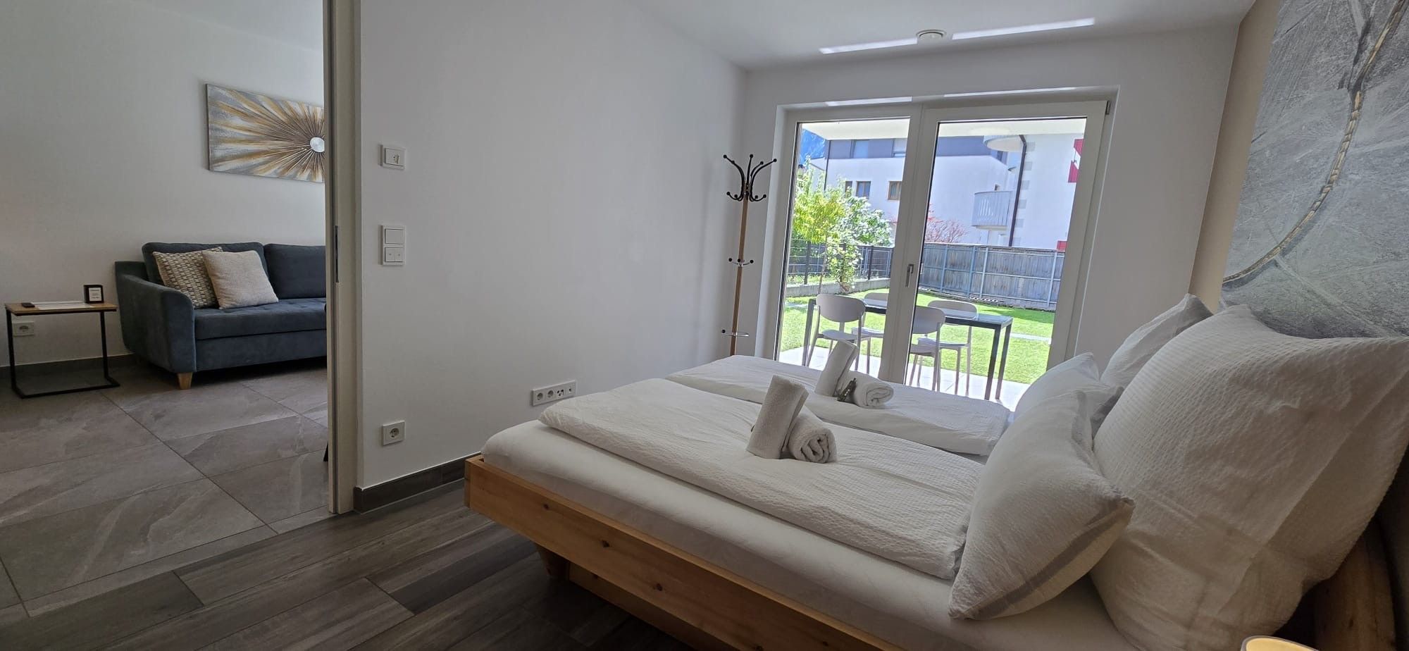 Ein Schlafzimmer mit Bett, Sofa und Blick ins Freie.