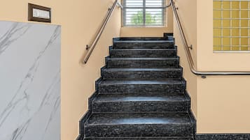 A staircase with black marble steps, metal handrails, and a small window with a grid pattern.