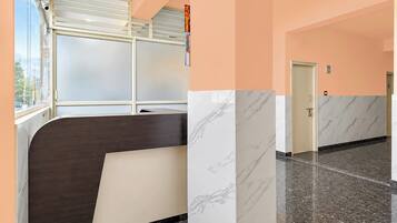 A hotel corridor with a reception desk, a door, and a window with blinds.