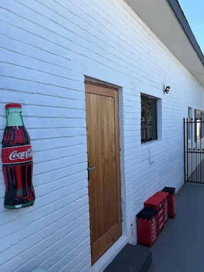 Ein weißes Gebäude mit Holztür, Fenster und einer Coca-Cola-Dekoration.