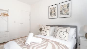 A hotel room with a bed, a bedside table, a lamp, a wardrobe, and two framed pictures on the wall.