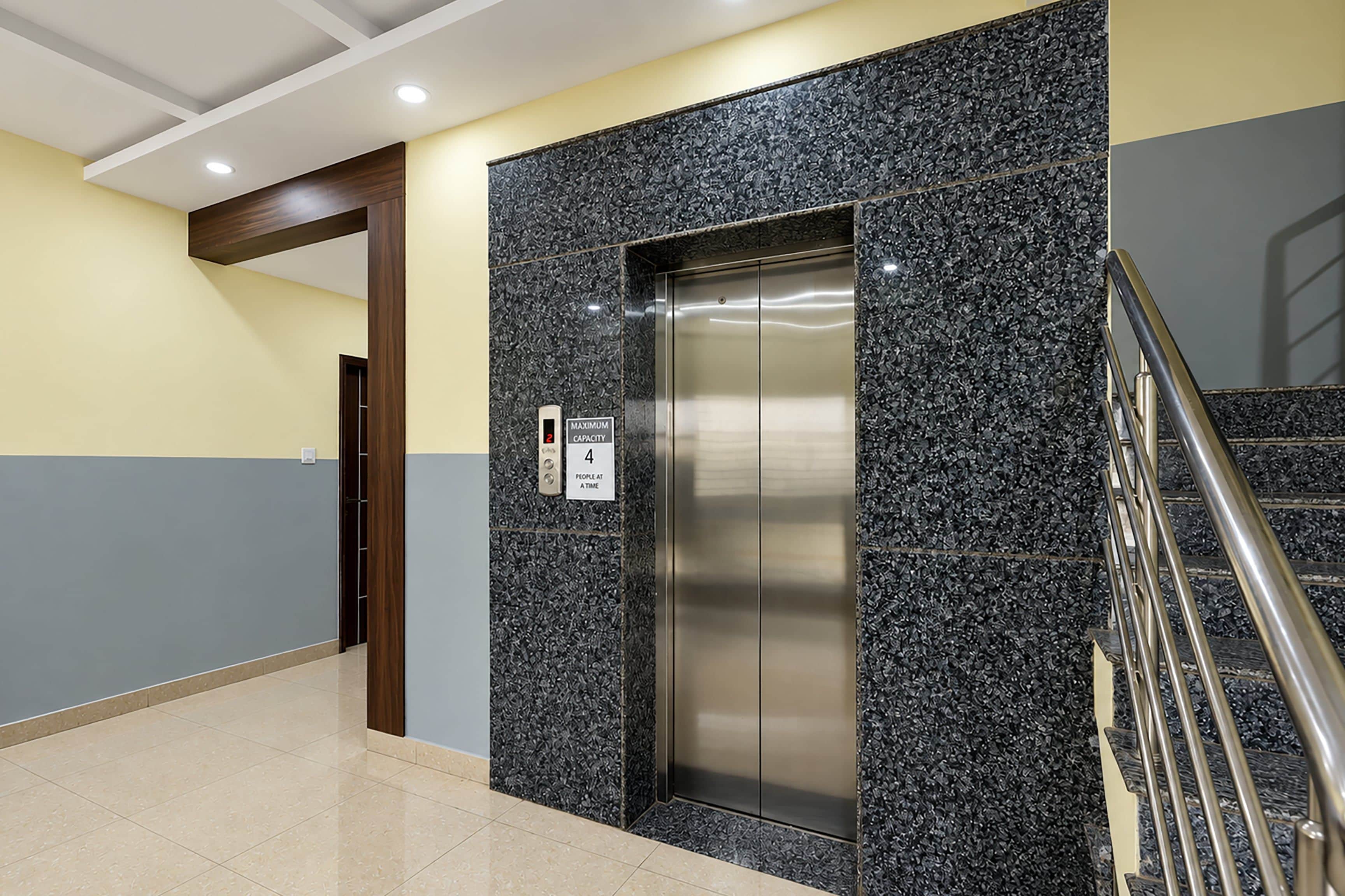 An elevator with a digital display, a maximum capacity sign, and a door with a wooden frame.