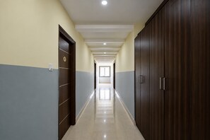 A corridor with a tiled floor, wooden doors, and a ceiling with recessed lighting. - Townhouse Airport Road Bangalore (Bengaluru)