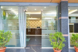 A hotel entrance with a glass door, a reception desk, and potted plants. - Townhouse Airport Road Bangalore (Bengaluru)