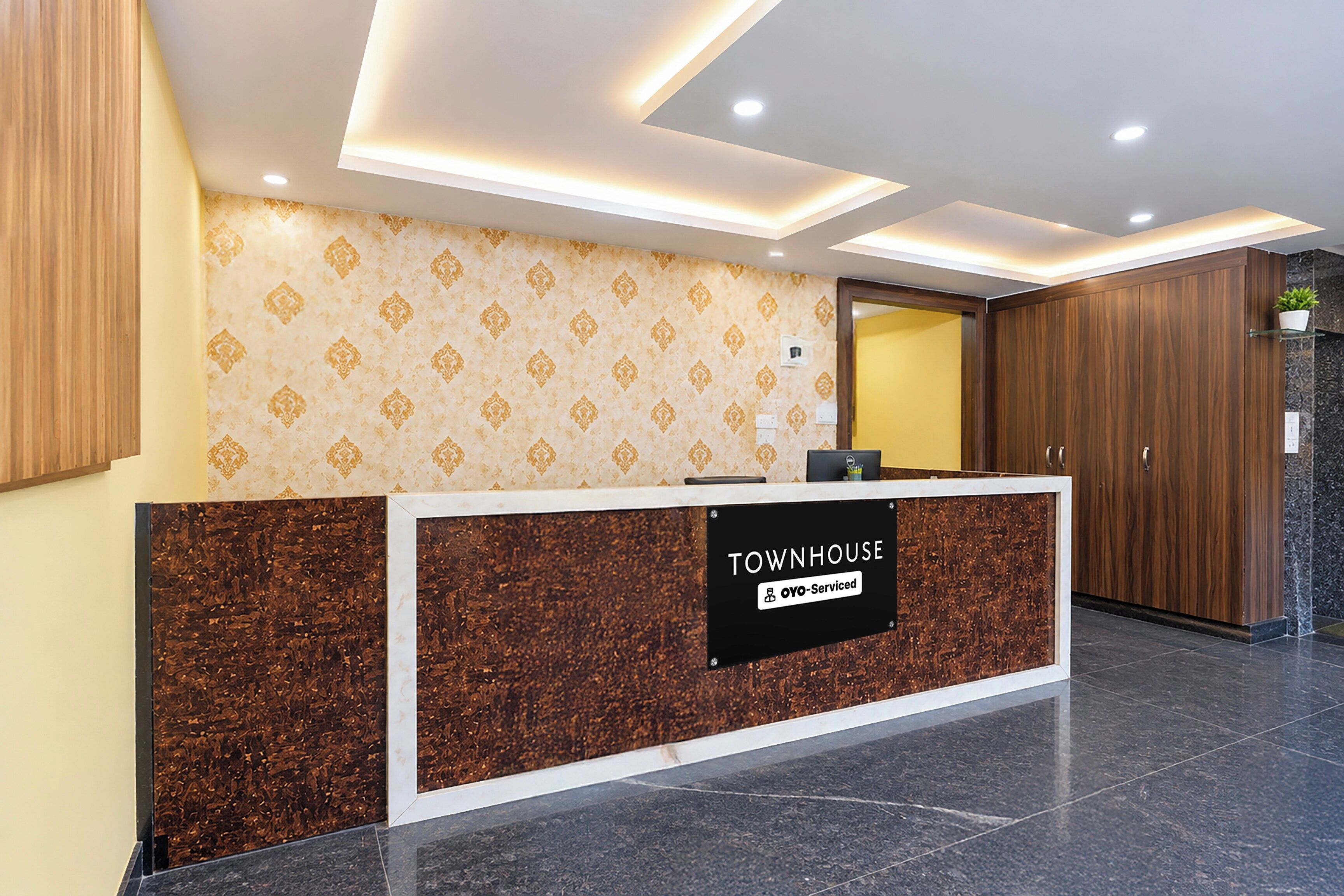 Un mostrador de recepción con un cartel que dice 'TOWNHOUSE' y 'OYO-Serviced'.