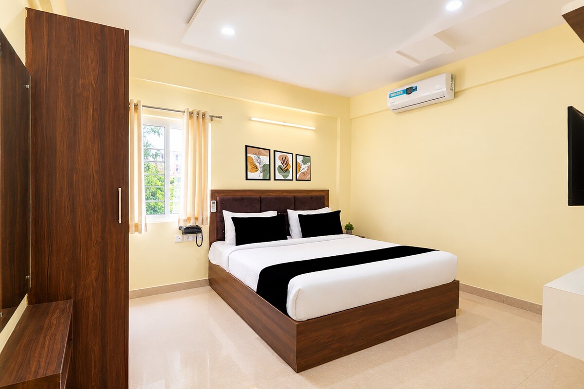 A hotel room with a wooden bed frame, a flat-screen TV, and a window with curtains.