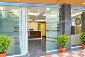 A reception area with a glass partition, a reception desk, and two potted plants. - Townhouse Airport Road Bangalore (Bengaluru)