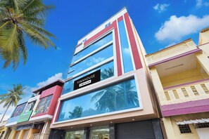 A multi-story building with a prominent 'TOWNHOUSE' sign, large windows, and a reflection of palm trees. - Townhouse Airport Road Bangalore (Bengaluru)