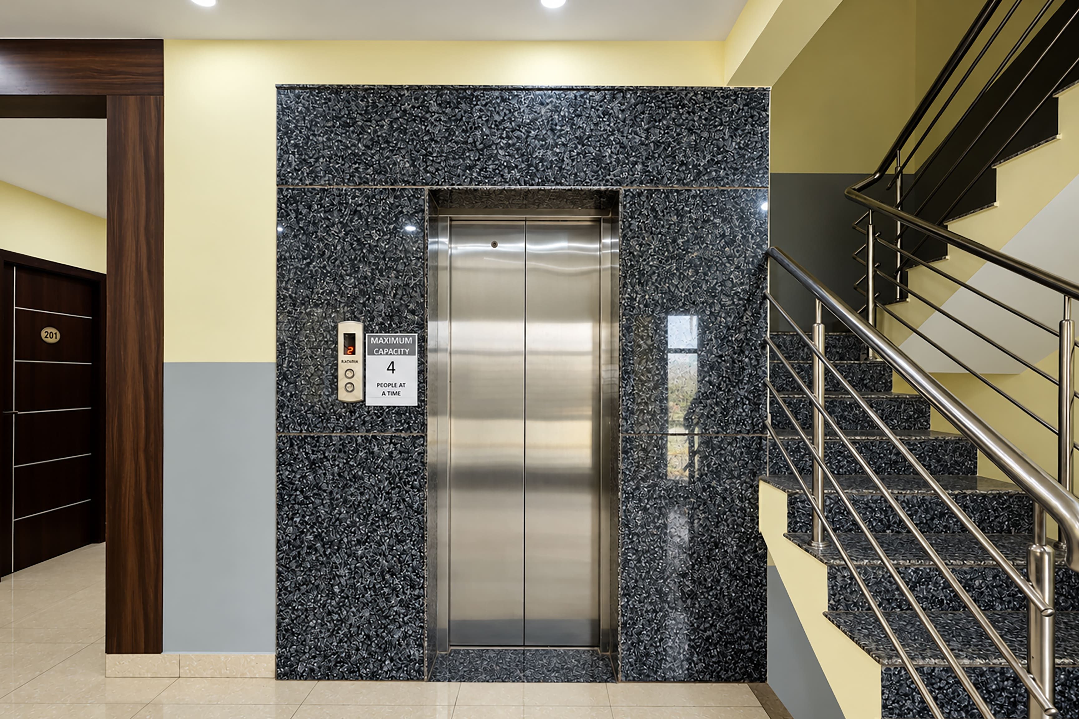 Un ascensor con un cartel de capacidad máxima, una pantalla digital y un panel de control.