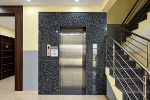 An elevator with a maximum capacity sign, a digital display, and a control panel. - Townhouse Airport Road Bangalore (Bengaluru)