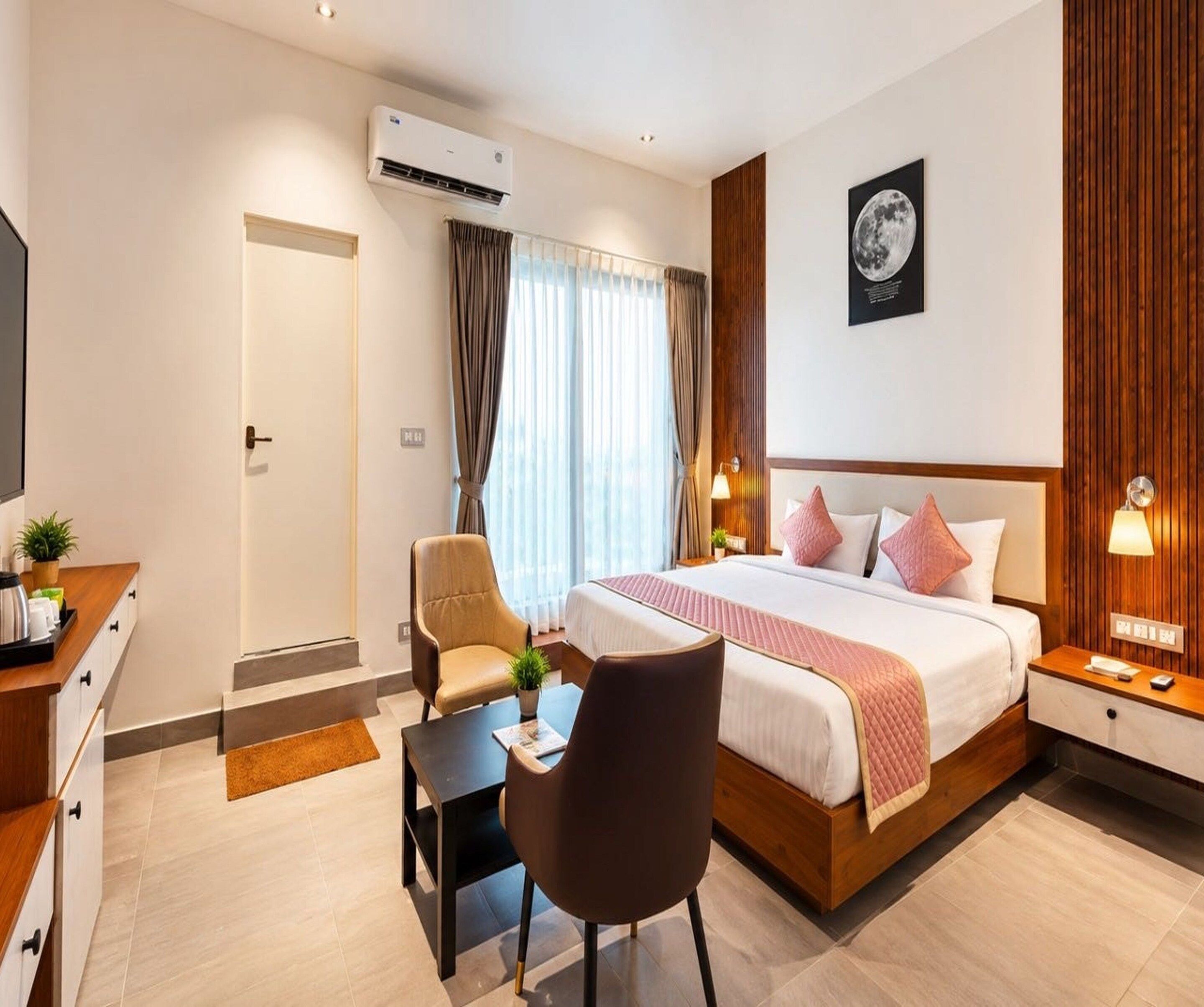 Una habitación de hotel con cama, mesitas de noche, escritorio, silla y aire acondicionado.