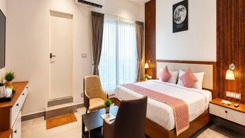 Una habitación de hotel con cama, mesitas de noche, escritorio, silla y aire acondicionado.