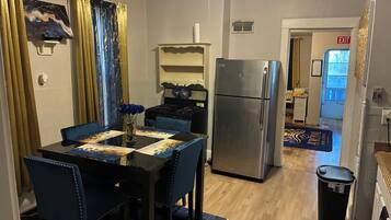 A compact kitchen with a refrigerator, stove, and dining area with chairs and a table.