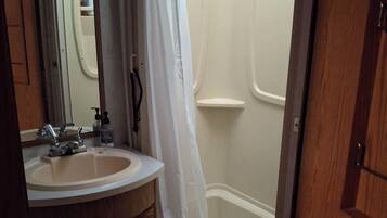 Un baño con lavabo, espejo y ducha.