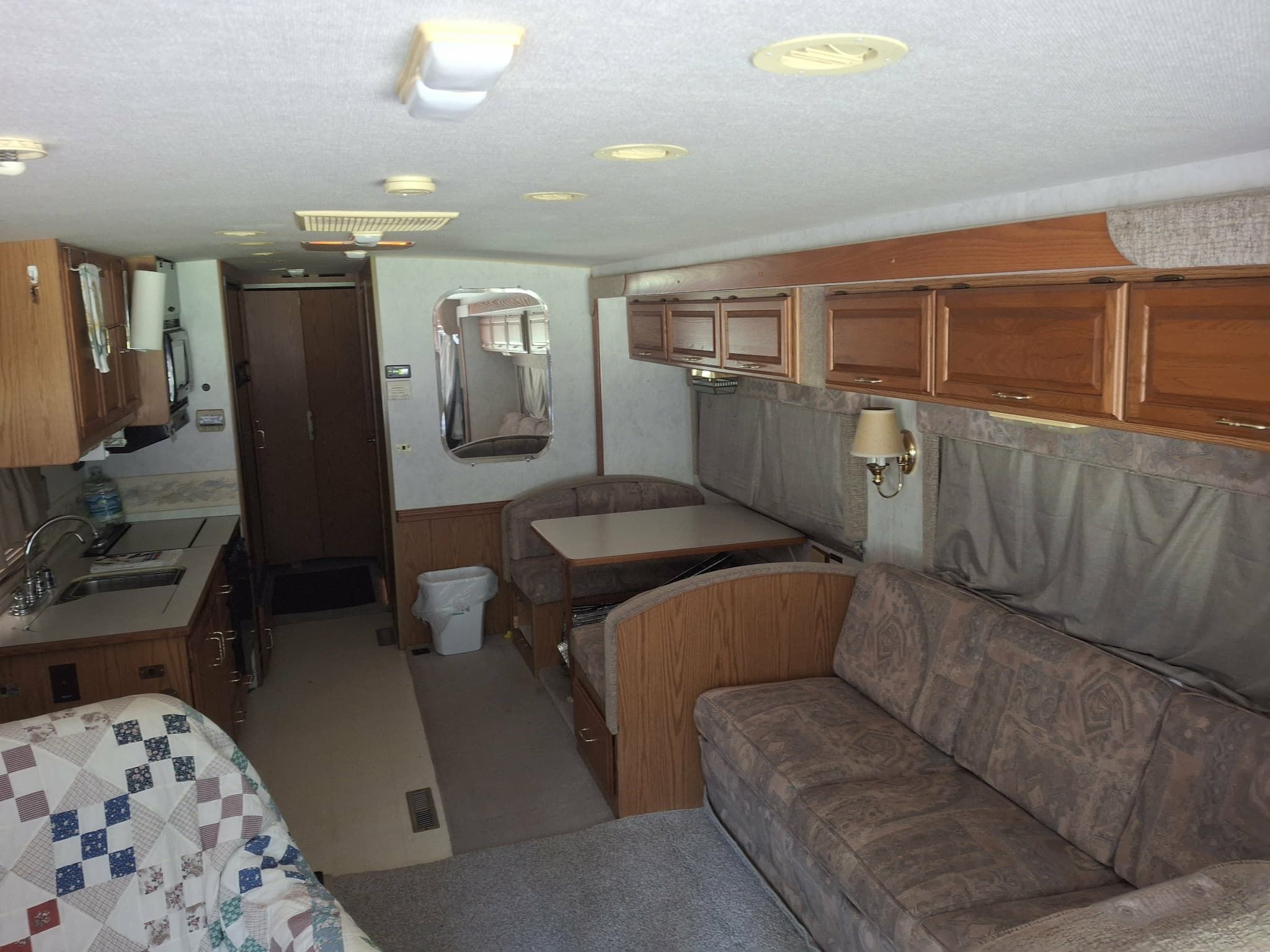 Interior compacto de una caravana con kitchenette, zona de comedor y área de estar.