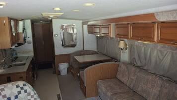 Interior compacto de una caravana con kitchenette, zona de comedor y área de estar.
