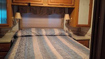 Un dormitorio con cama, armarios de madera y dos lámparas fijadas a la pared.