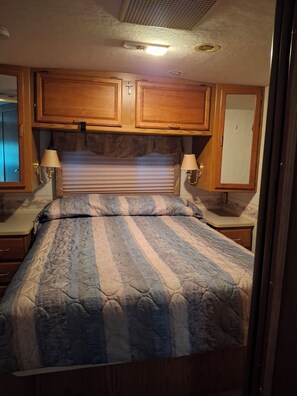 A bedroom with a bed, wooden cabinets, and two wall-mounted lamps.