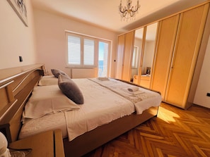 A bedroom with a wooden bed, a large mirror, a wardrobe, and a radiator. - A6 - Spacious apartment with pool, 5 balconies and the sea view, near beach (Omiš)