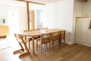 A dining area with a round wooden table and six chairs, a white radiator, and a wooden cabinet. - D.Í.G Gøta 31, ST. (Thorshavn)