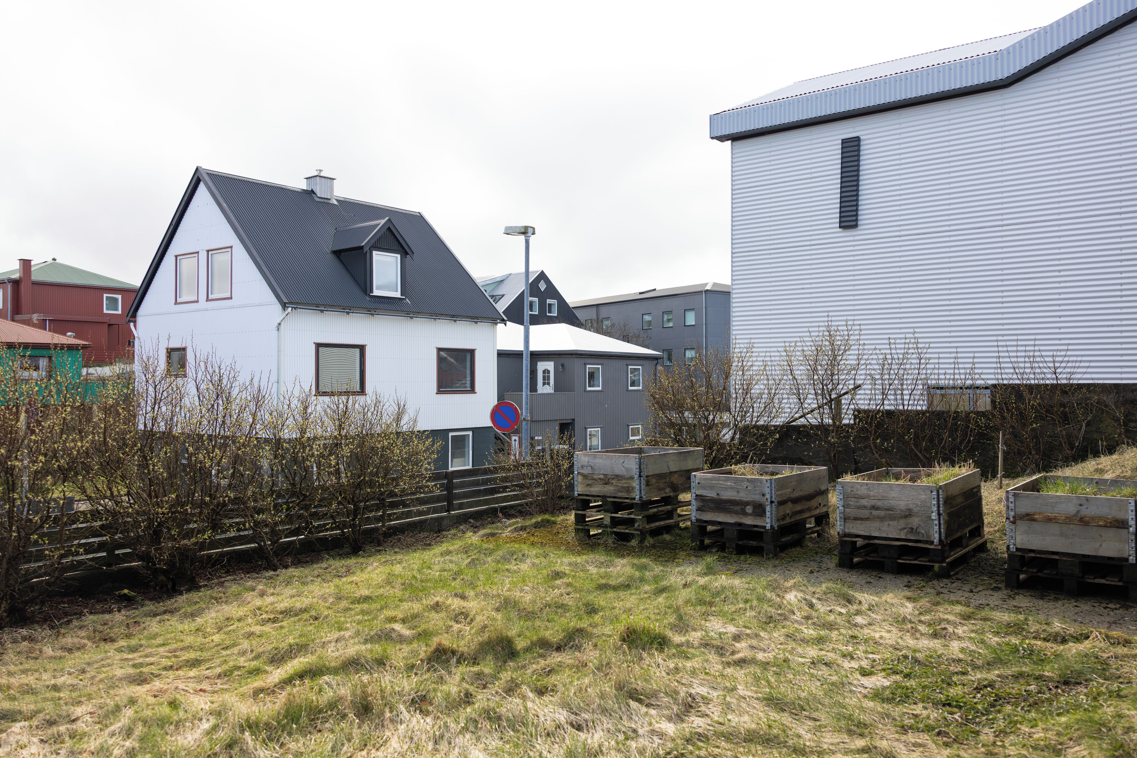 A residential area with houses, a no parking sign, and wooden pallets.