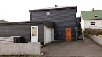 A building with a dark exterior, a white garage door, and a wooden door.