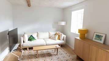 A modern living room with a sofa, a coffee table, a TV, a lamp, a window, and a cabinet.