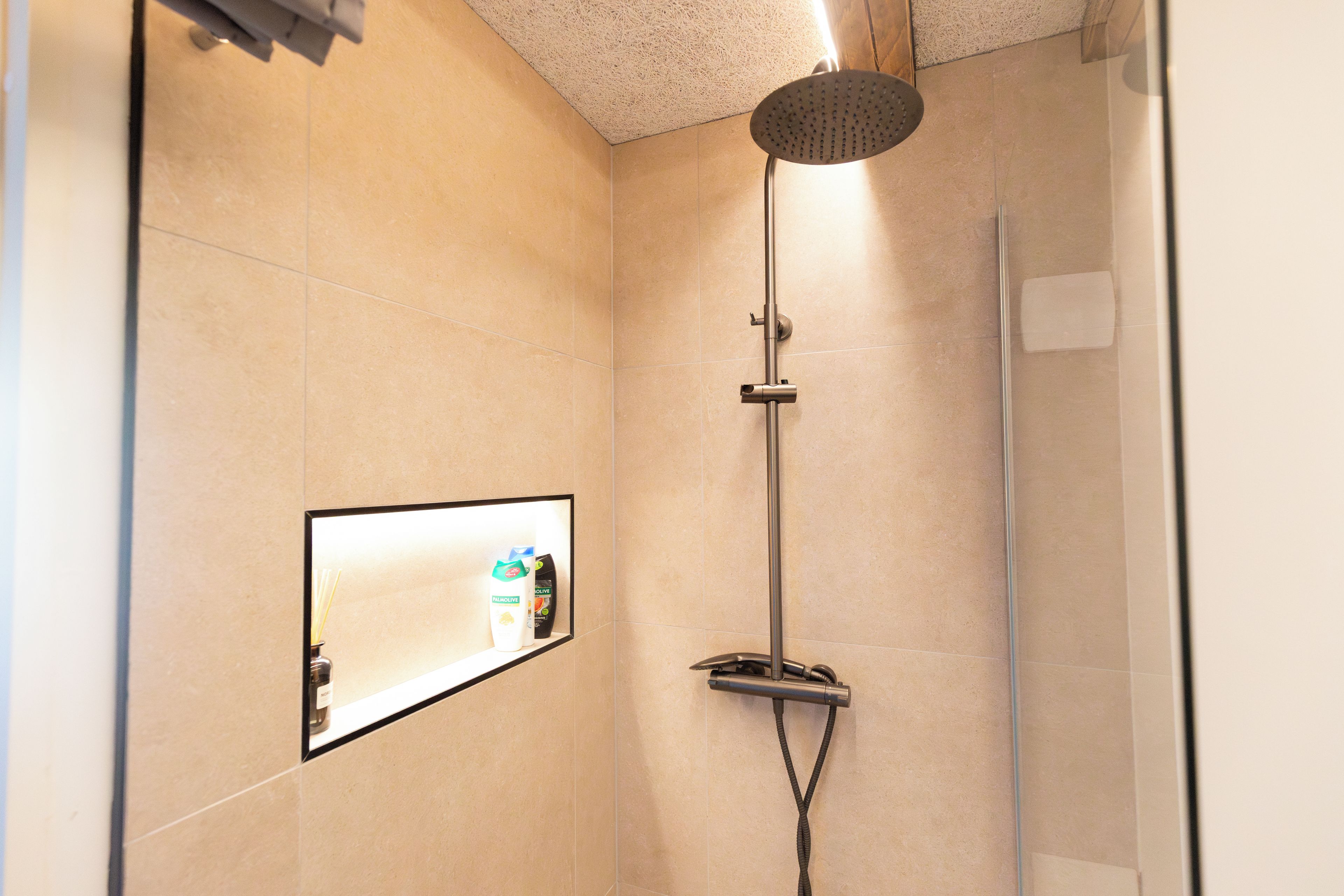 A modern bathroom with a shower, a mirror, and toiletries.