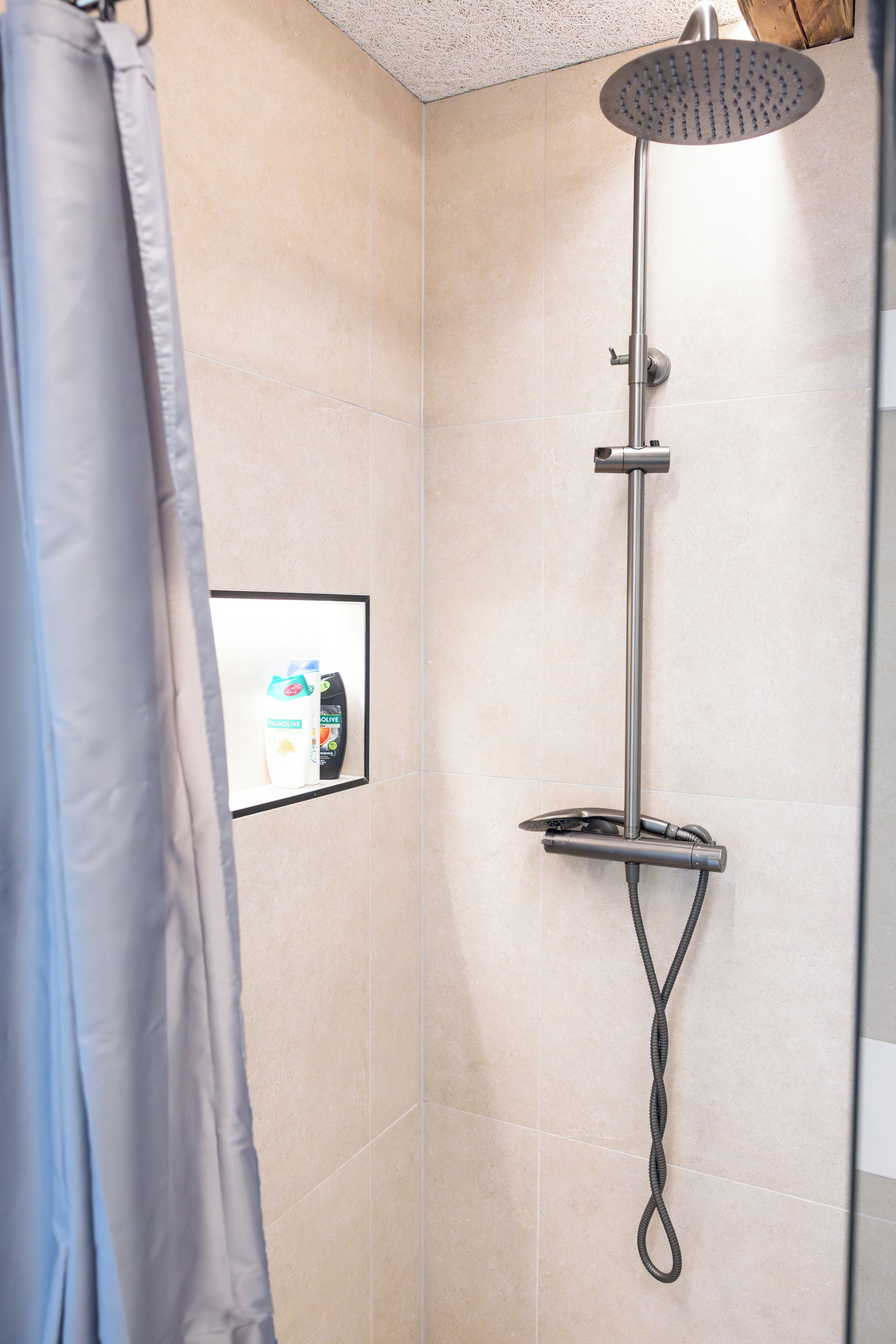 A shower with a handheld showerhead, a handheld showerhead, and a handheld showerhead.