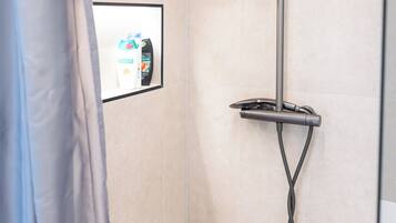 A shower with a handheld showerhead, a handheld showerhead, and a handheld showerhead.