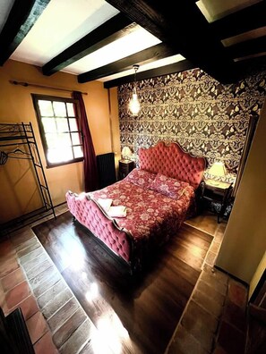 Ein Schlafzimmer mit einem großen Bett, Holzboden, Wand mit Muster und einer hängenden Leuchte.